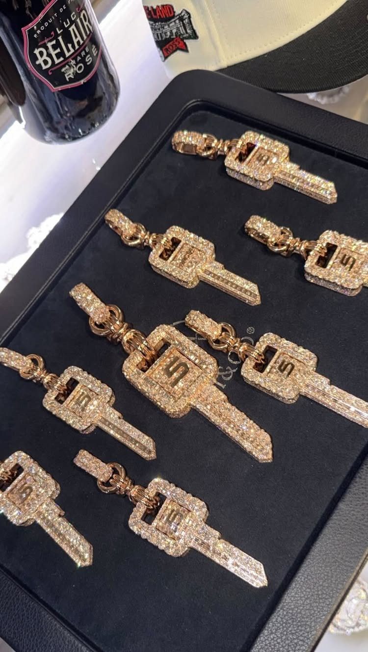 Gold key pendants encrusted with diamonds resting on a black velvet display tray