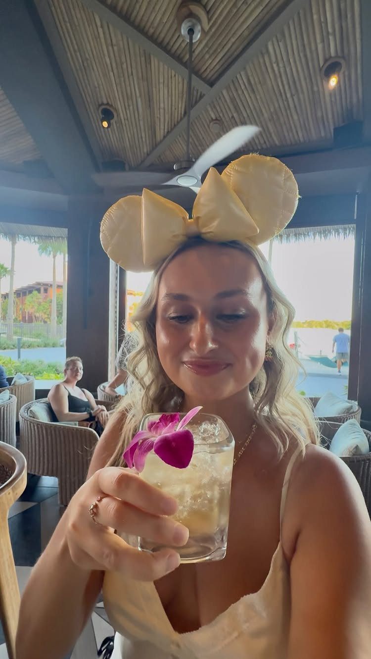 Woman wearing Minnie Mouse ears holding a cocktail in a Disney resort lounge