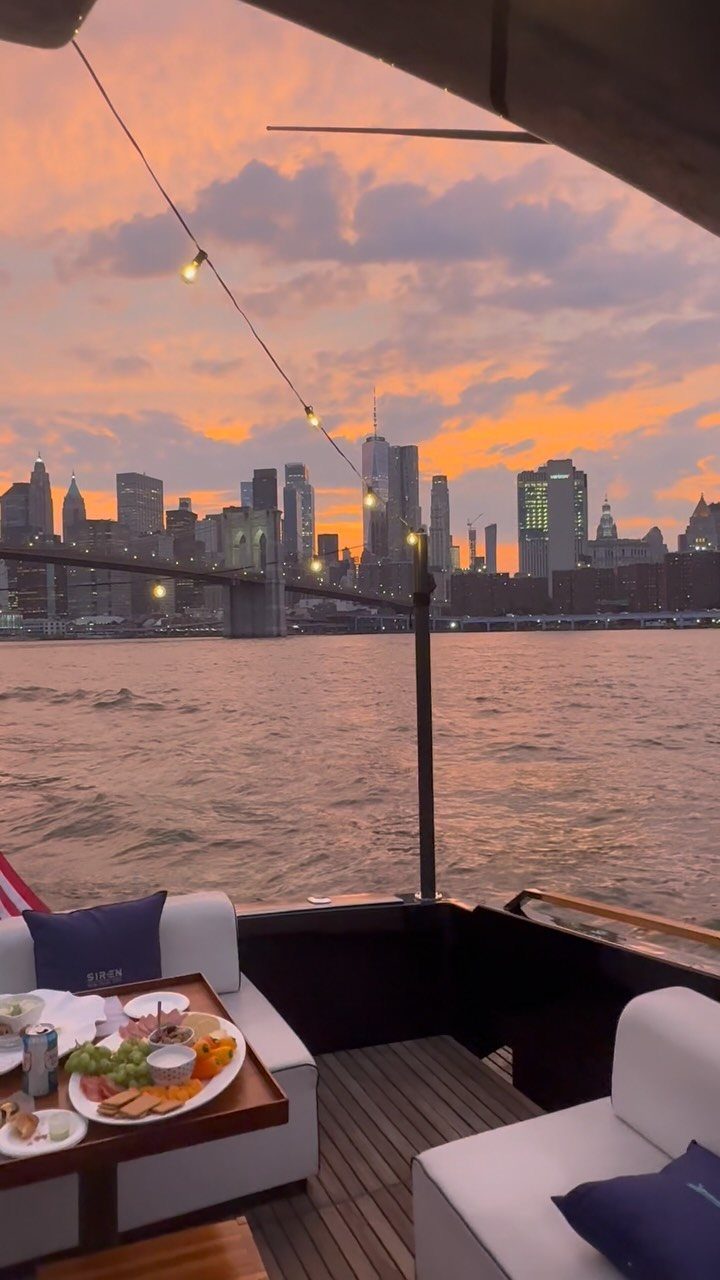 Boat deck with appetizers overlooking the New York City skyline during a sunset.