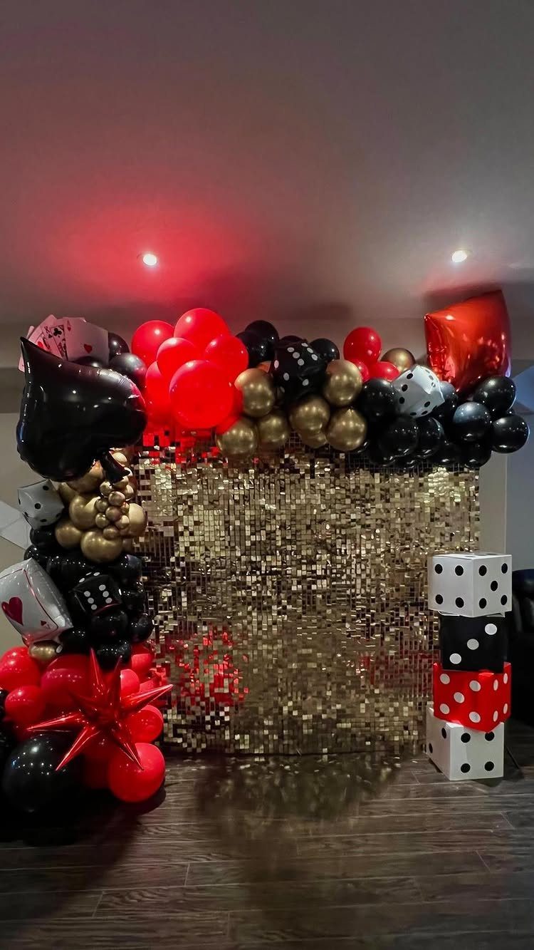 Gold sequin backdrop with red, black, and gold balloons and large dice decorations.