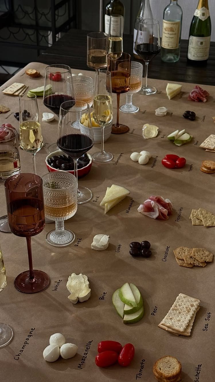 Wine glasses and a charcuterie spread with handwritten labels on brown parchment paper.