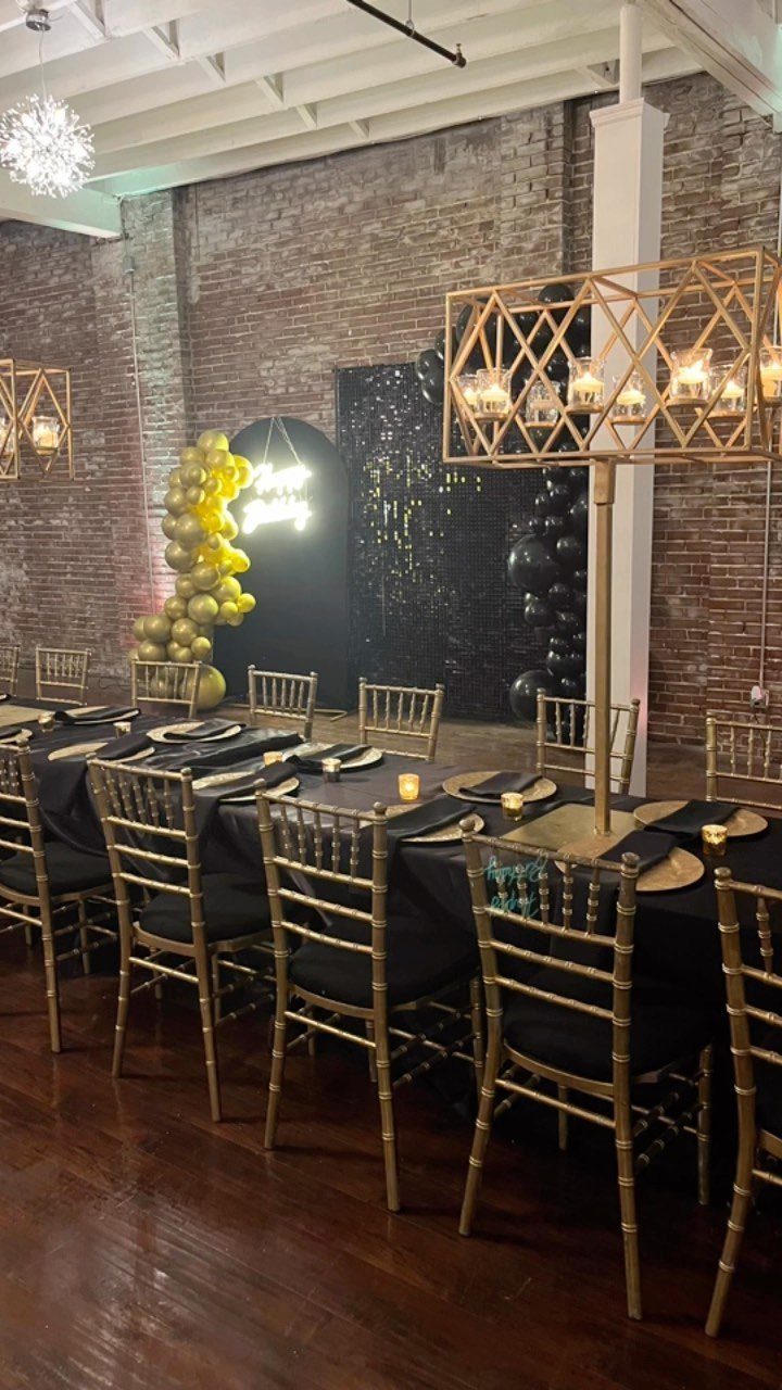 Dining table with gold chairs set against an exposed red brick wall backdrop.