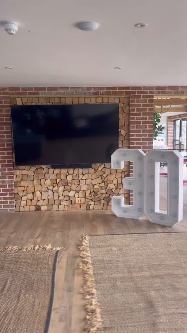 Large white marquee numbers 30 standing in a room with brick walls.