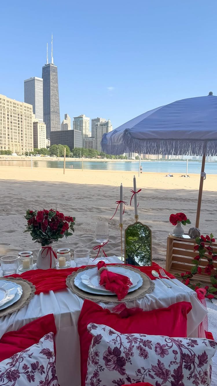 Luxury beach picnic setup with red accents and city skyline in the background