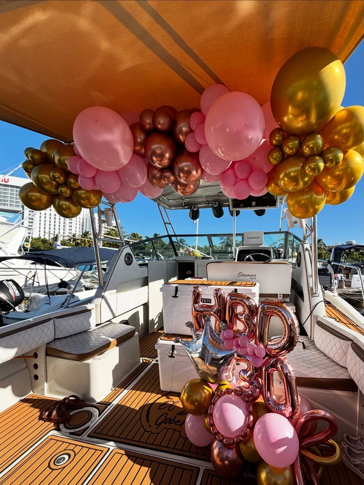 Luxury yacht deck decorated with pink and gold balloons and HBD 30 foil balloons.