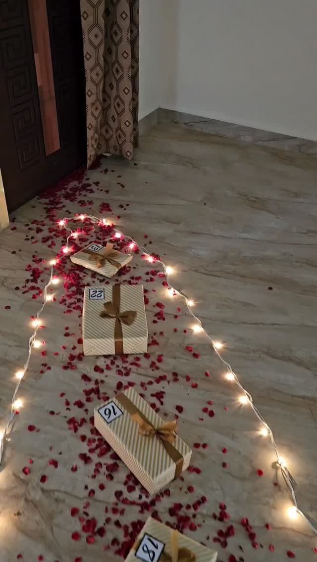 Wrapped gift boxes with ribbons and numbered tags among rose petals and fairy lights.