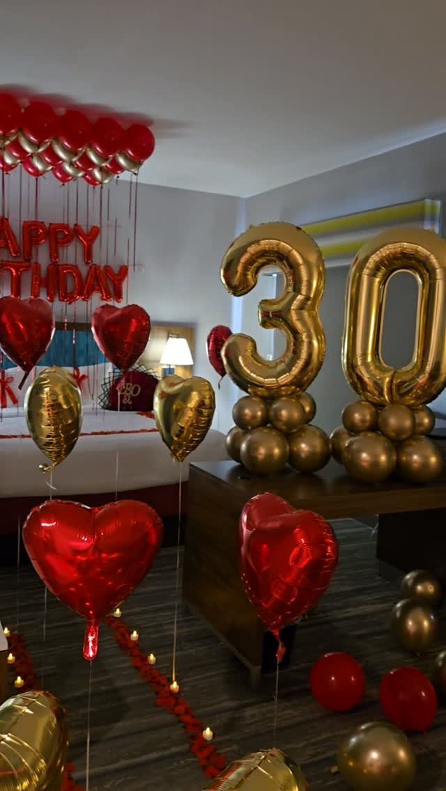 Gold number 30 balloons and red heart balloons decorating a birthday room.