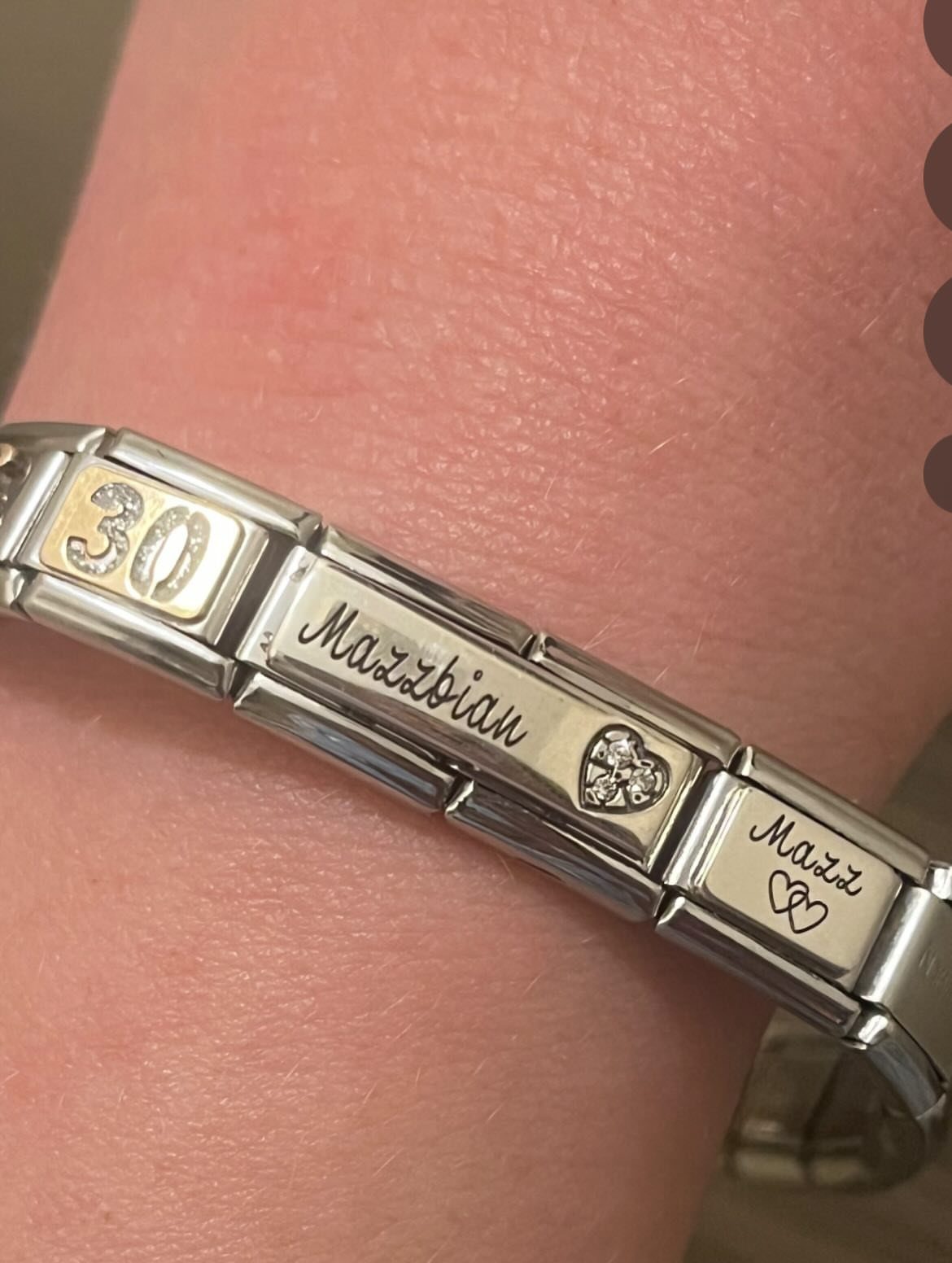 Silver engraved bracelet on a wrist featuring the number 30 and personalized names.