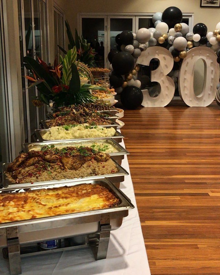 Buffet food trays and large white number 30 balloons for a birthday party