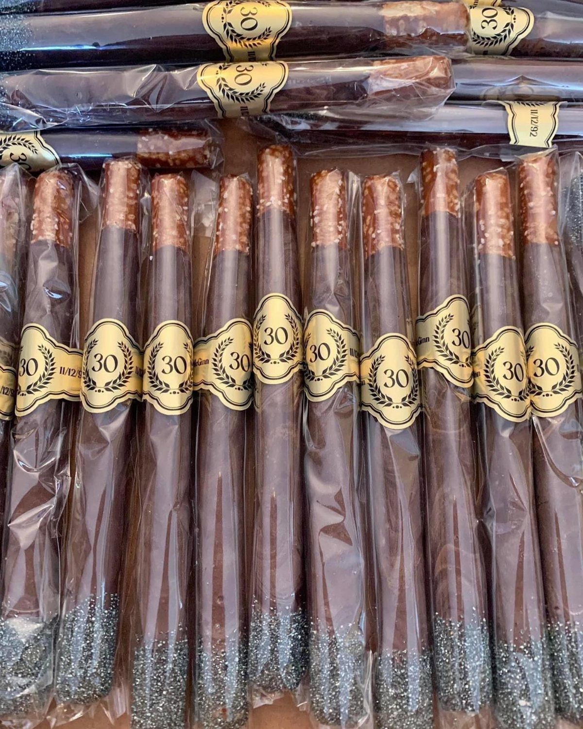 Chocolate covered pretzel rods with silver glitter and gold 30th birthday labels.