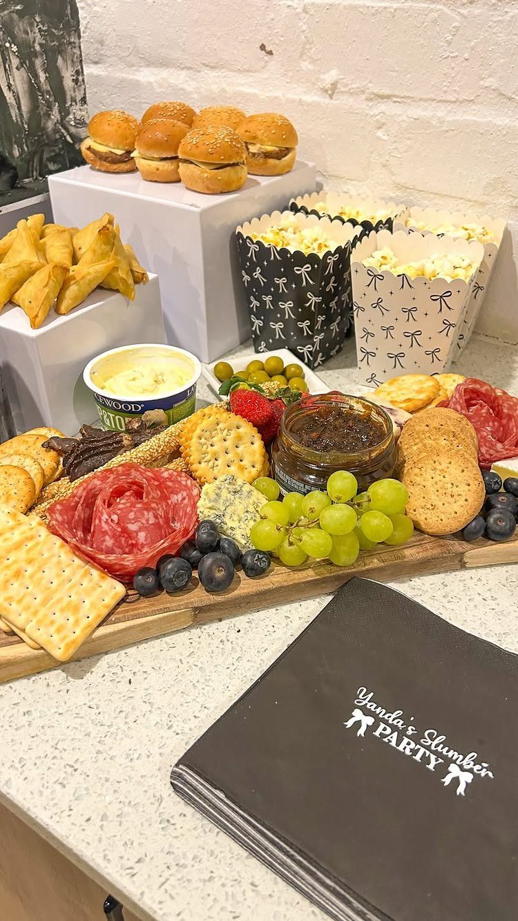 Party food spread with charcuterie and popcorn next to a Slumber Party folder.