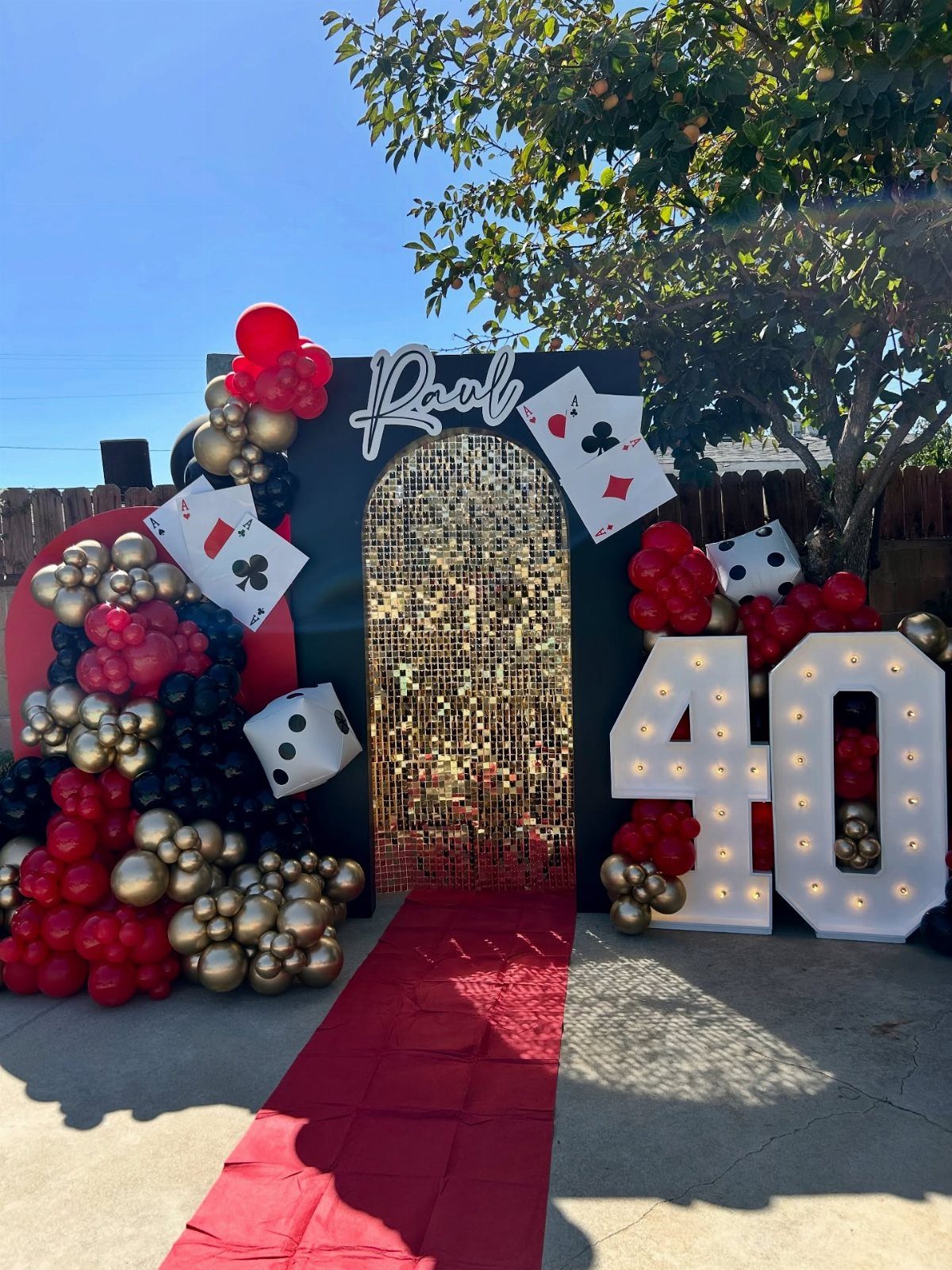 Casino themed 40th birthday decoration with red carpet, gold backdrop, and giant dice.