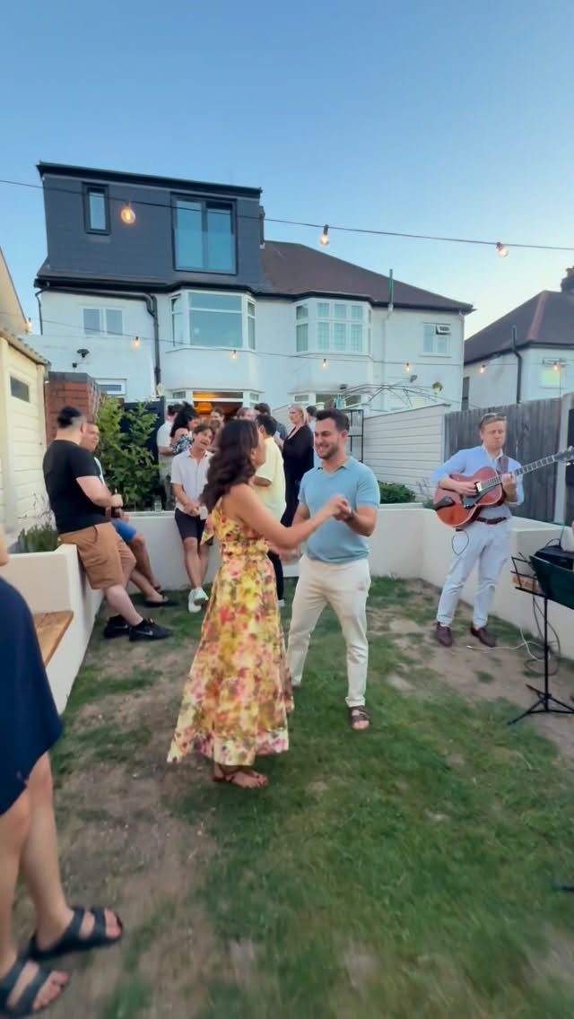 Couple dancing in a backyard party with a live acoustic guitar player performing.