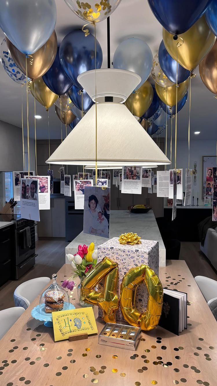 Gold 40 balloons and a gift on a table with hanging photo memories.