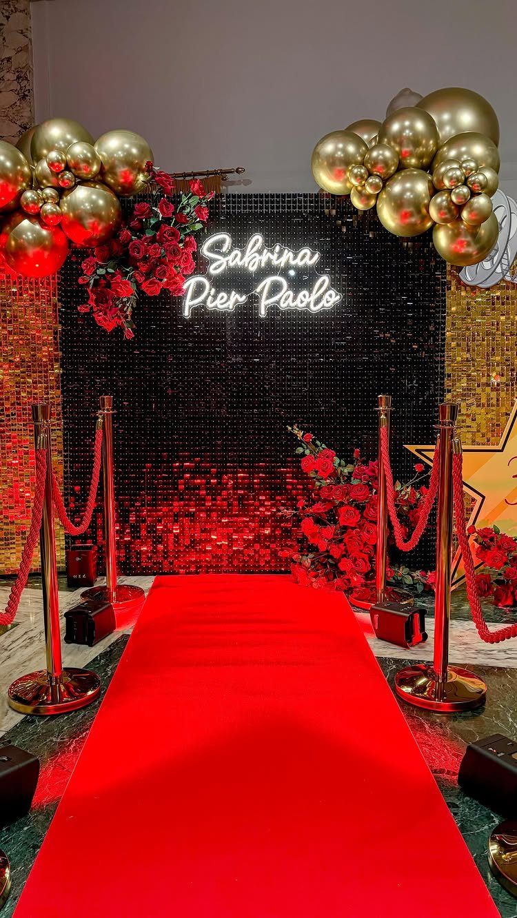 Red carpet entrance with gold stanchions, gold balloons, and a black sequin backdrop.