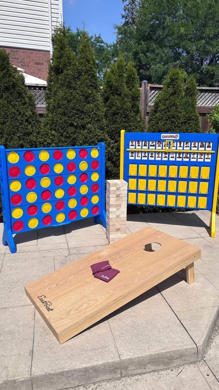 Wooden cornhole board with bean bags and giant lawn games on a patio.