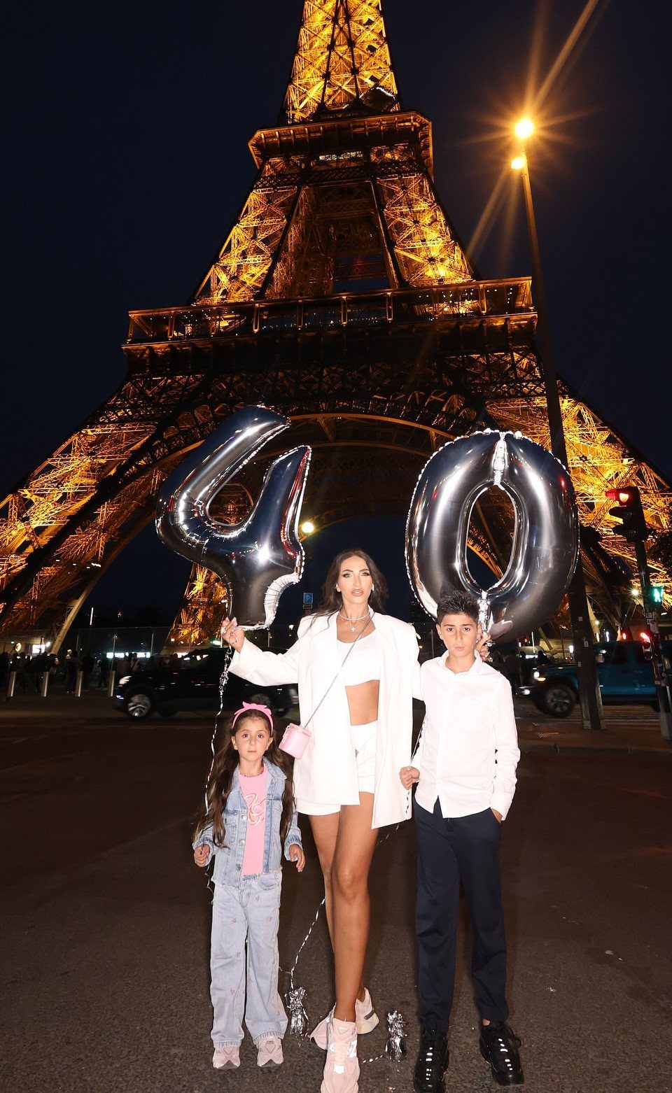 Woman and children with silver 40 balloons in front of the Eiffel Tower