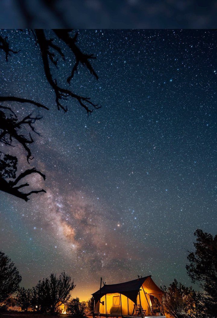 Illuminated glamping tent under a starry night sky with the Milky Way visible.