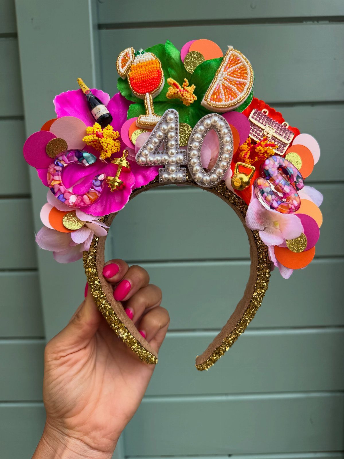 Gold glittery headband with pearl number 40 and colorful party decorations.