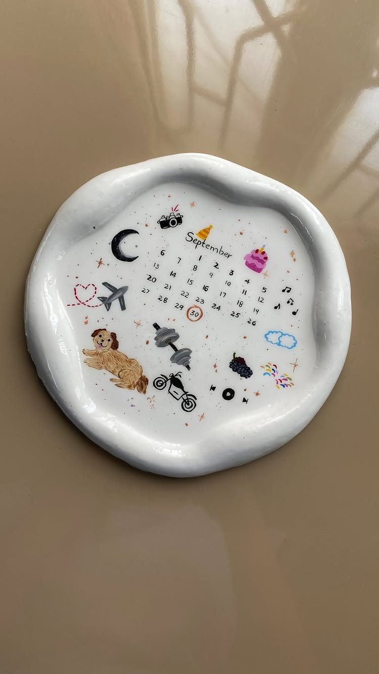 White ceramic trinket dish with a painted September calendar and colorful personalized illustrations