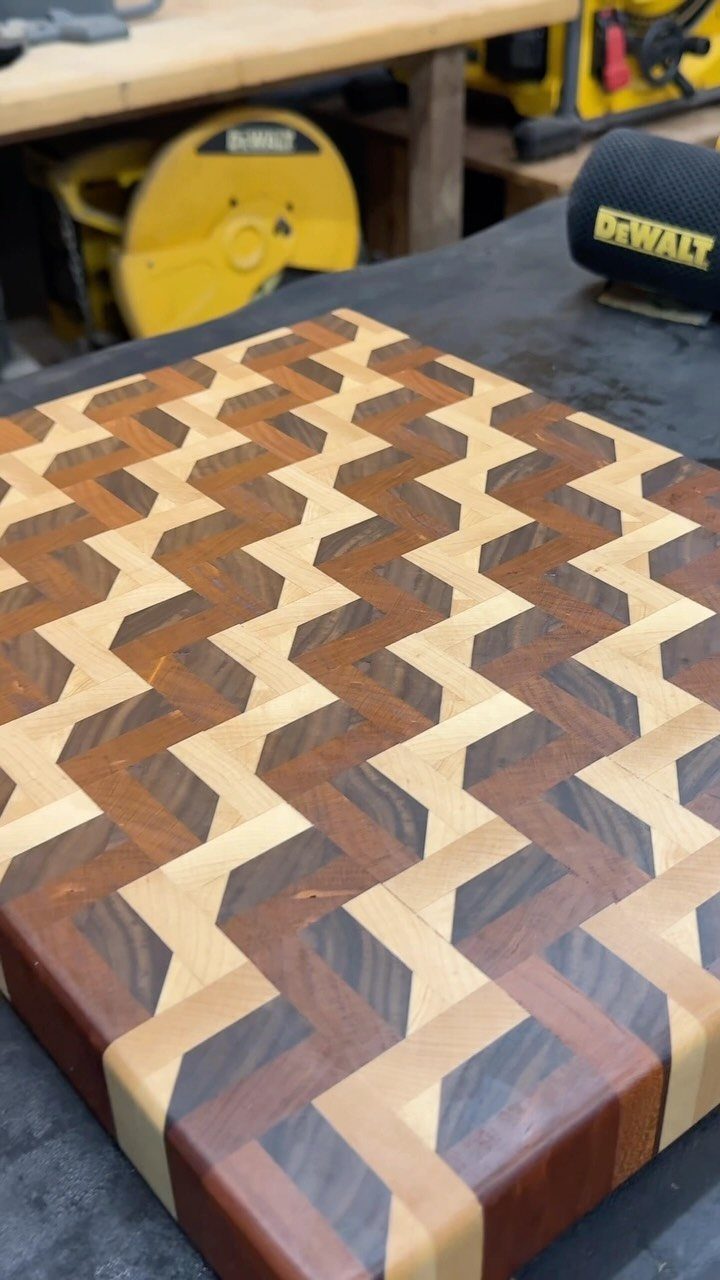 Wooden cutting board with a geometric chevron pattern on a workshop workbench.