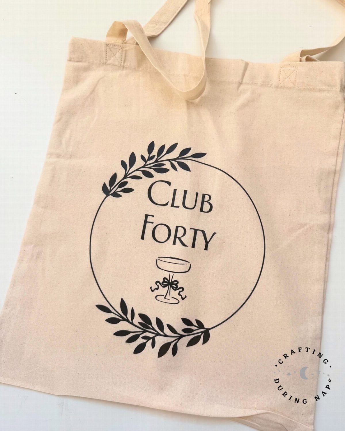 Beige canvas tote bag featuring a black Club Forty graphic and cocktail glass.