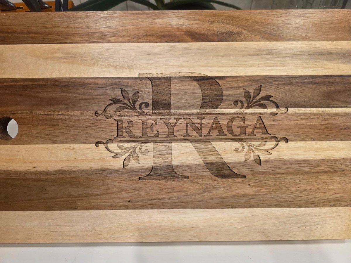 Wooden cutting board with engraved name Reynaga and decorative floral flourishes
