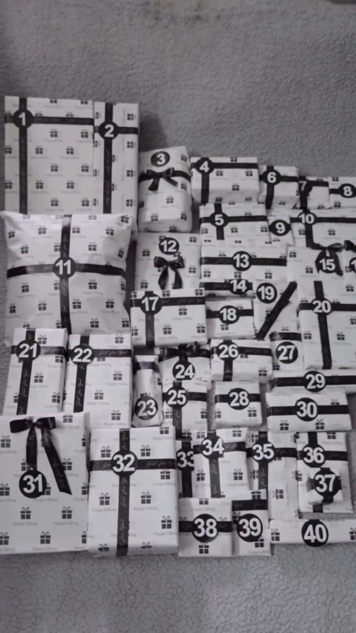 Forty wrapped white gifts with black ribbons and number tags for a birthday.