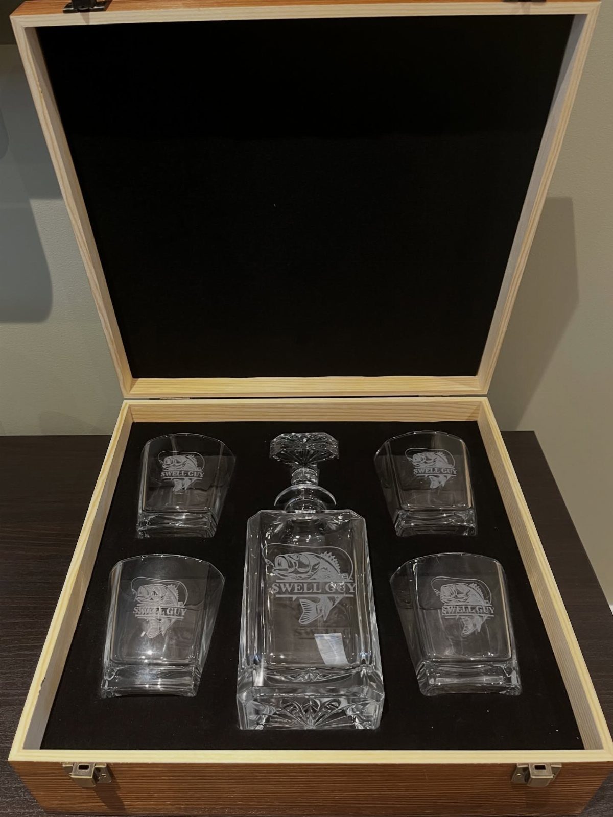 Engraved glass whiskey decanter and four glasses inside a wooden gift box.