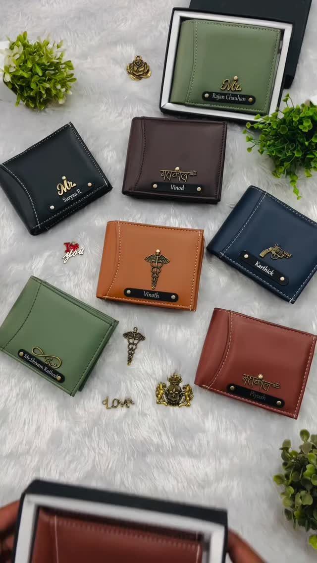 Assorted leather wallets with personalized gold nameplates on a white fluffy background.