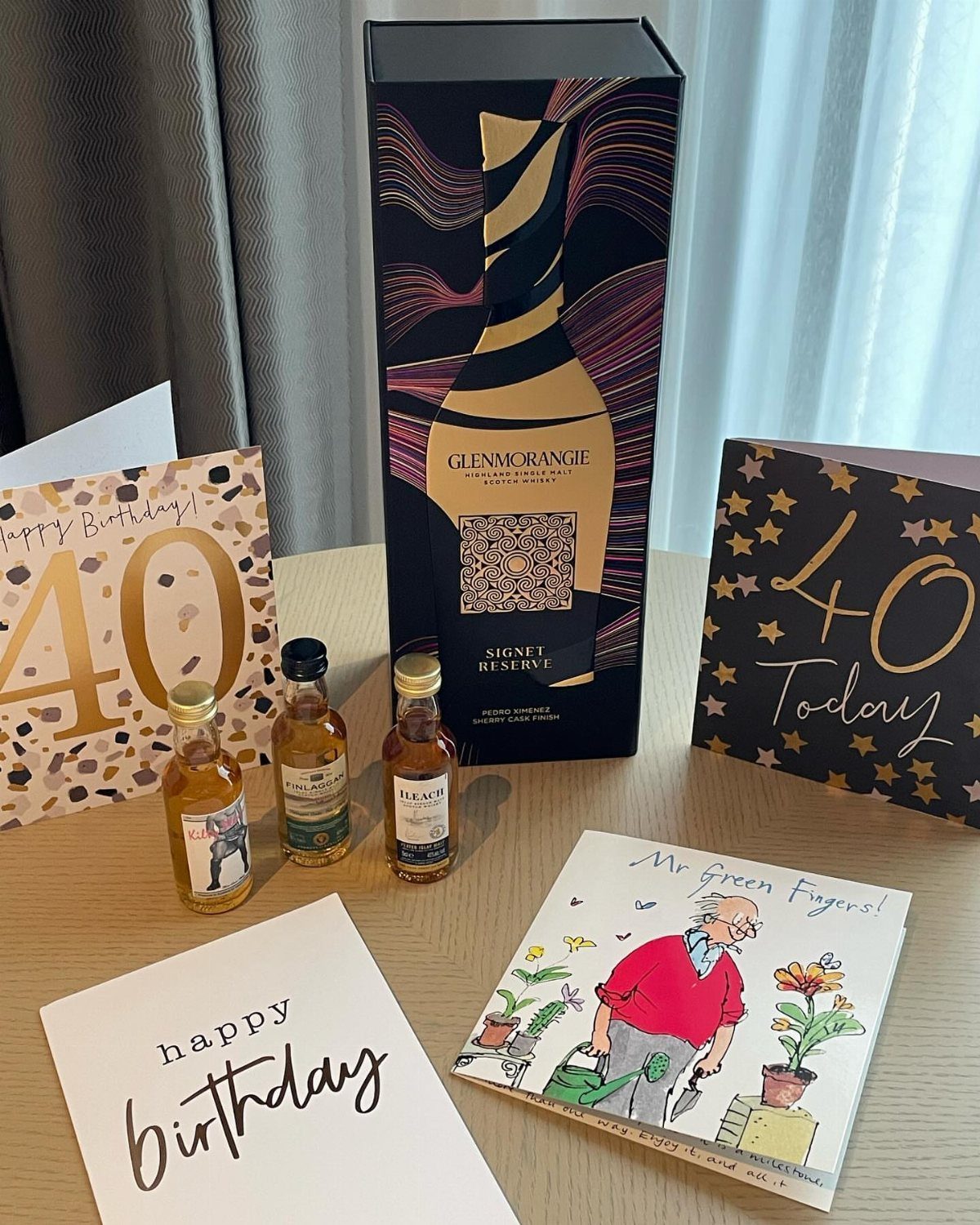 Whiskey bottles and a Glenmorangie gift box surrounded by 40th birthday cards.