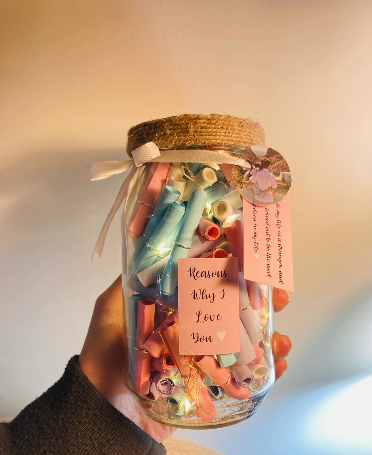 Glass jar filled with colorful rolled notes and fairy lights as a gift