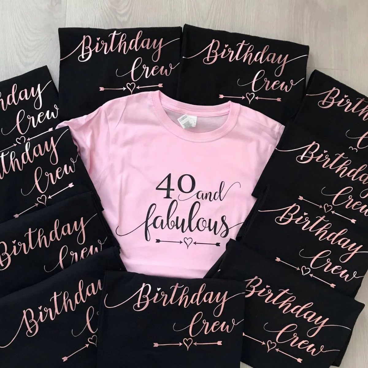 Pink 40th birthday t-shirt surrounded by black Birthday Crew shirts on a floor