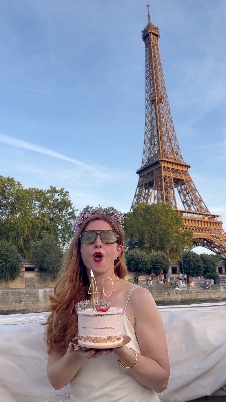 Woman holding a 40th birthday cake in front of the Eiffel Tower in Paris
