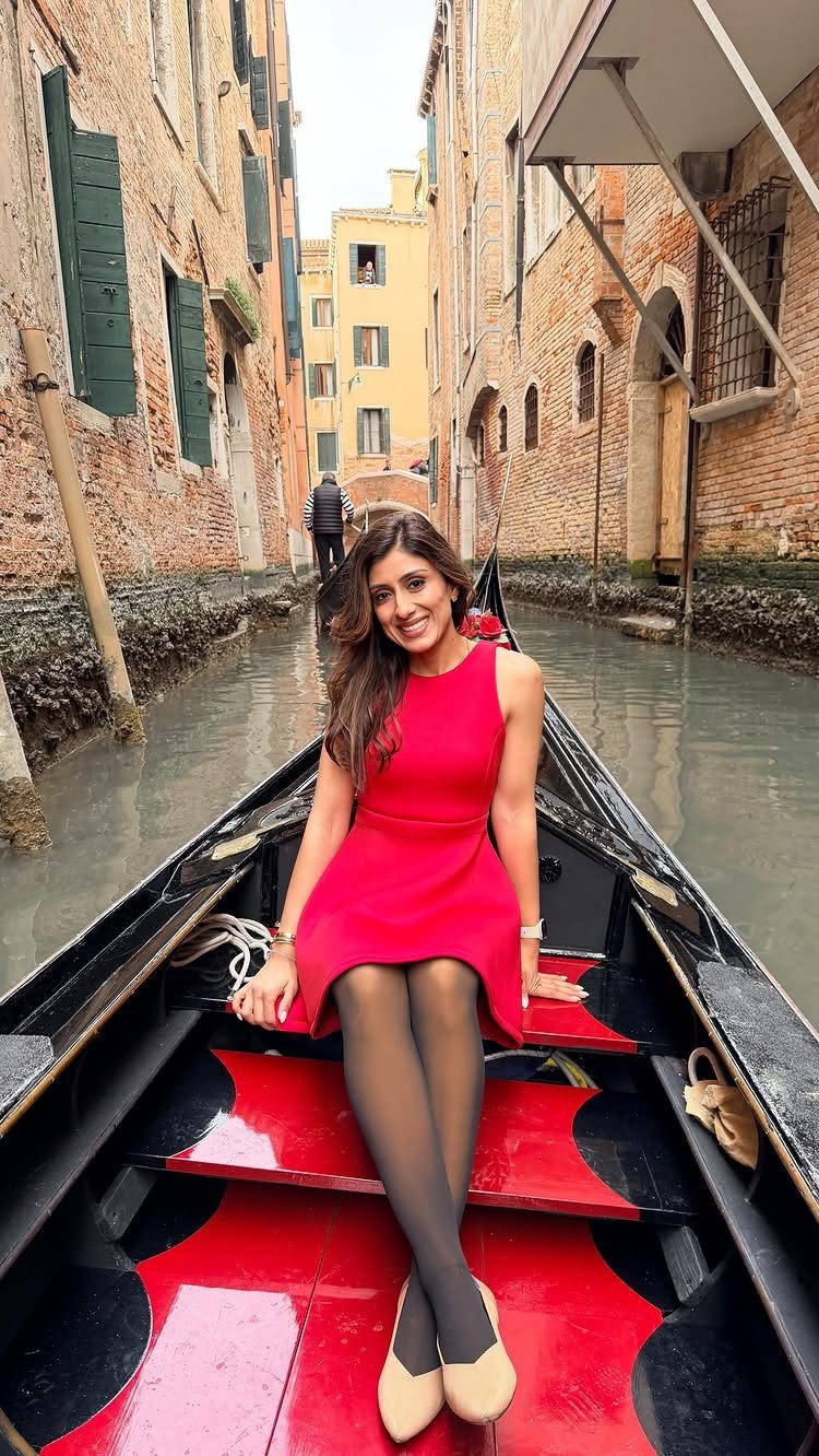Woman in red dress sitting in a gondola on a Venice canal