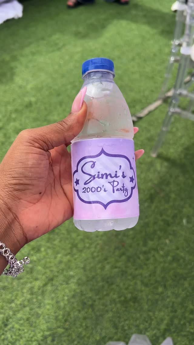 Water bottle with a purple label for Simi's 2000's Party held by hand.
