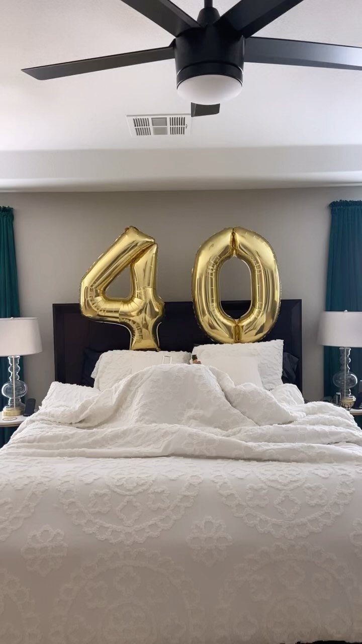 Gold foil balloons forming the number 40 on a white bed
