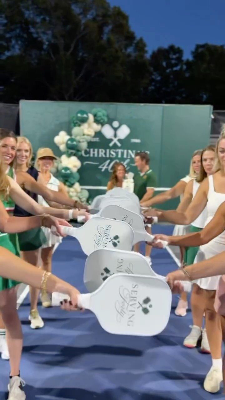 Women holding pickleball paddles in a circle for a 40th birthday celebration party.
