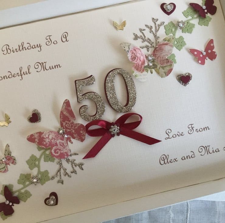 Cream birthday card with glittery gold 50, red ribbon, and floral butterfly embellishments.