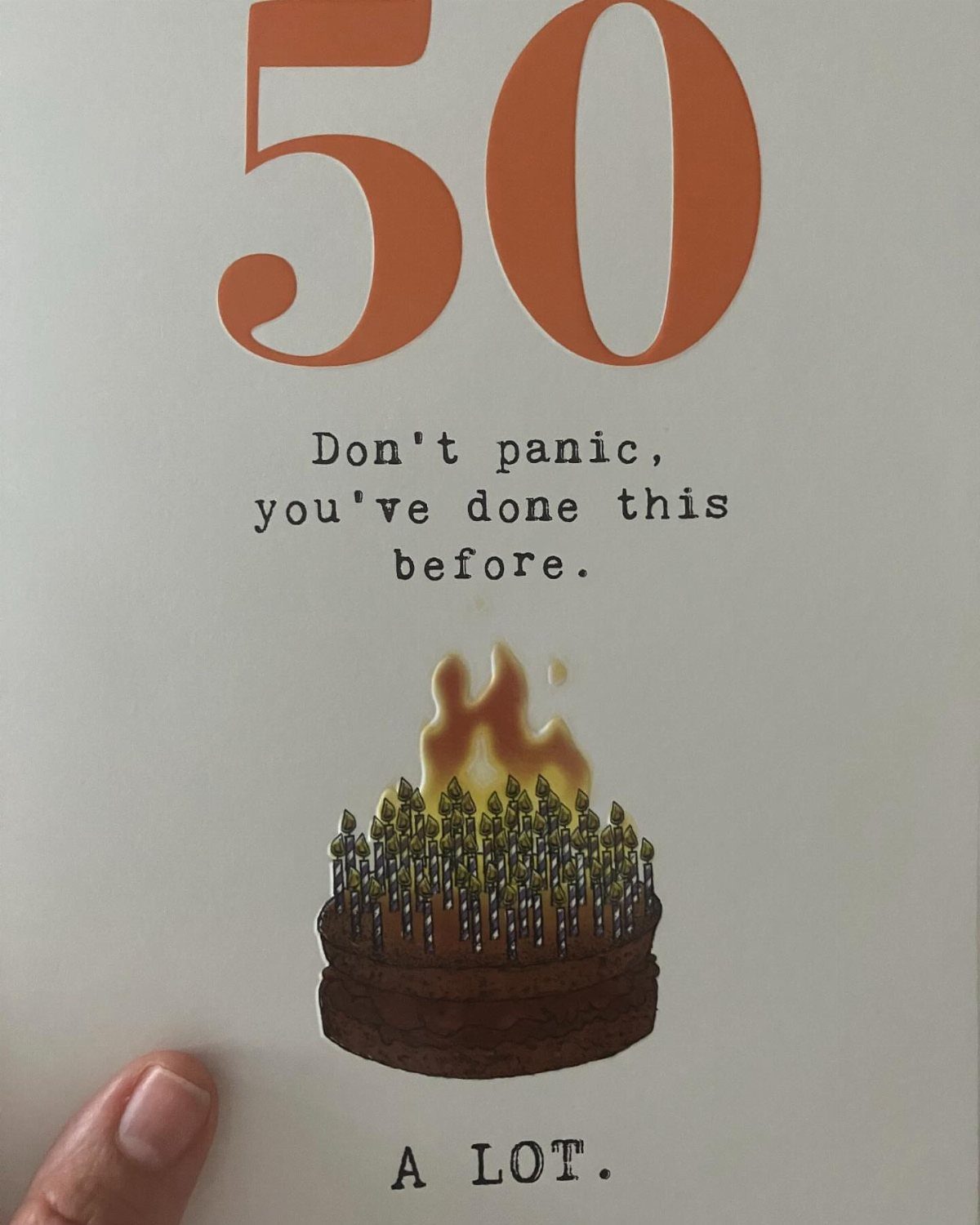 Birthday card with orange 50 and a chocolate cake engulfed in flames.