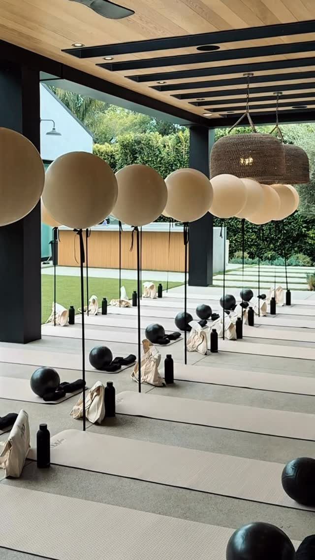 Yoga mats with exercise balls and floating beige balloons in a modern pavilion