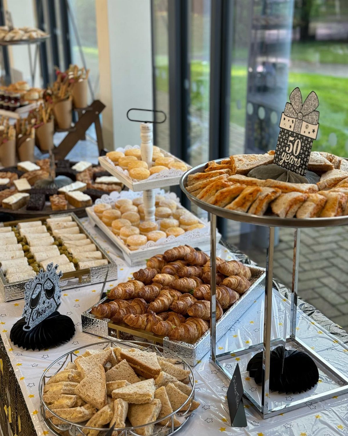Buffet table with croissants and pastries featuring a 50th birthday cake topper.