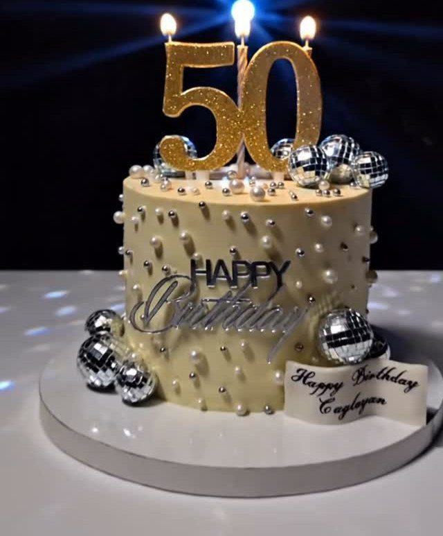 Cream birthday cake with gold 50 topper and silver disco ball decorations