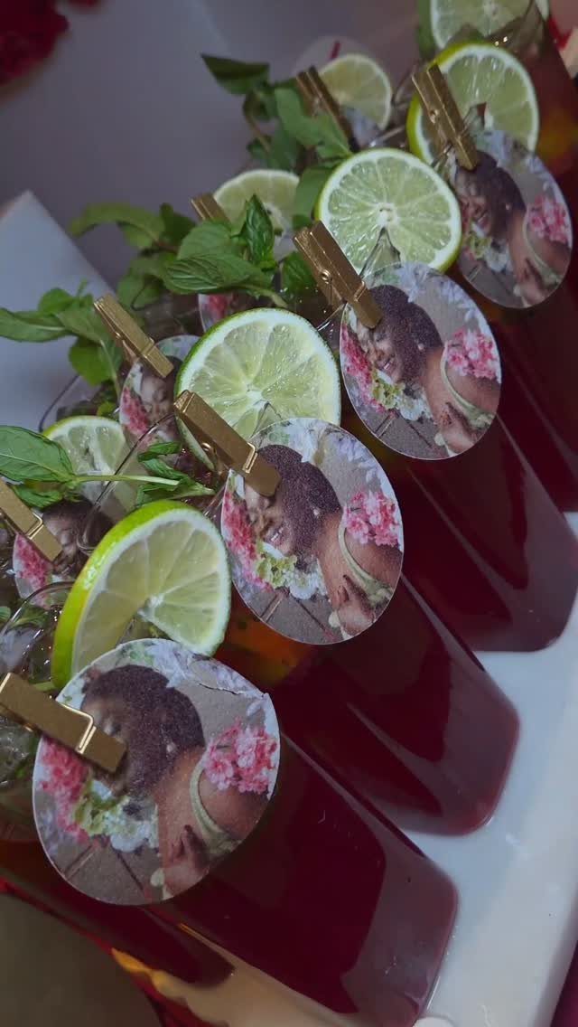 Red cocktails garnished with lime and mint, featuring personalized photo clips on rims.