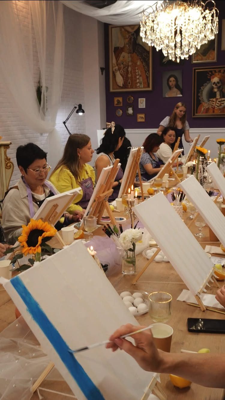 Women painting on canvases at a decorated table during a birthday party activity.