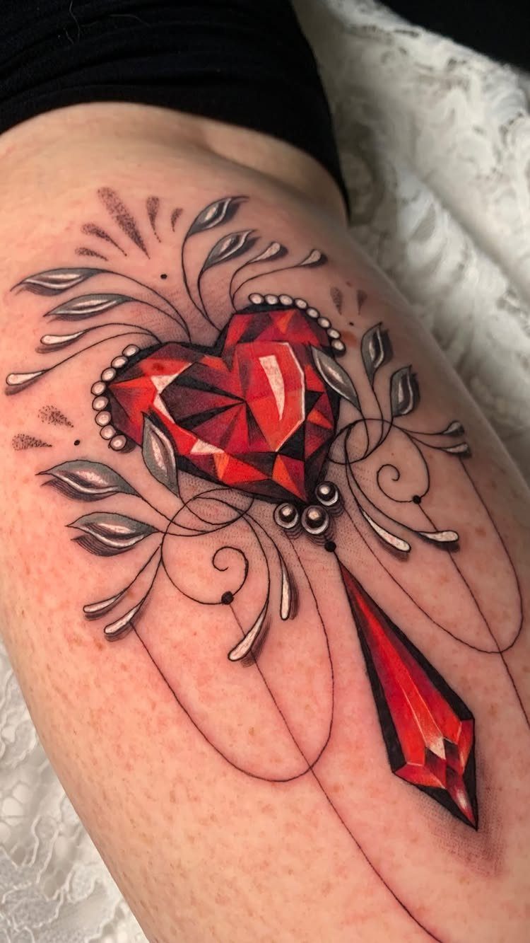 Red gemstone heart tattoo with a crystal drop and grey leaf accents