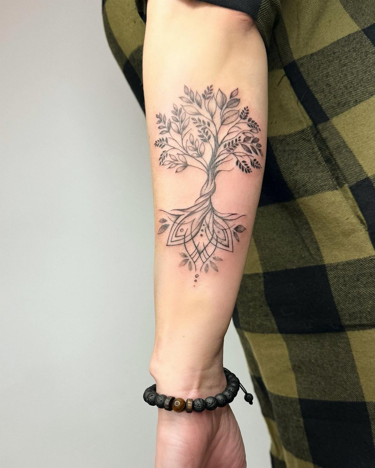 Tree of life tattoo with geometric roots on a person's forearm