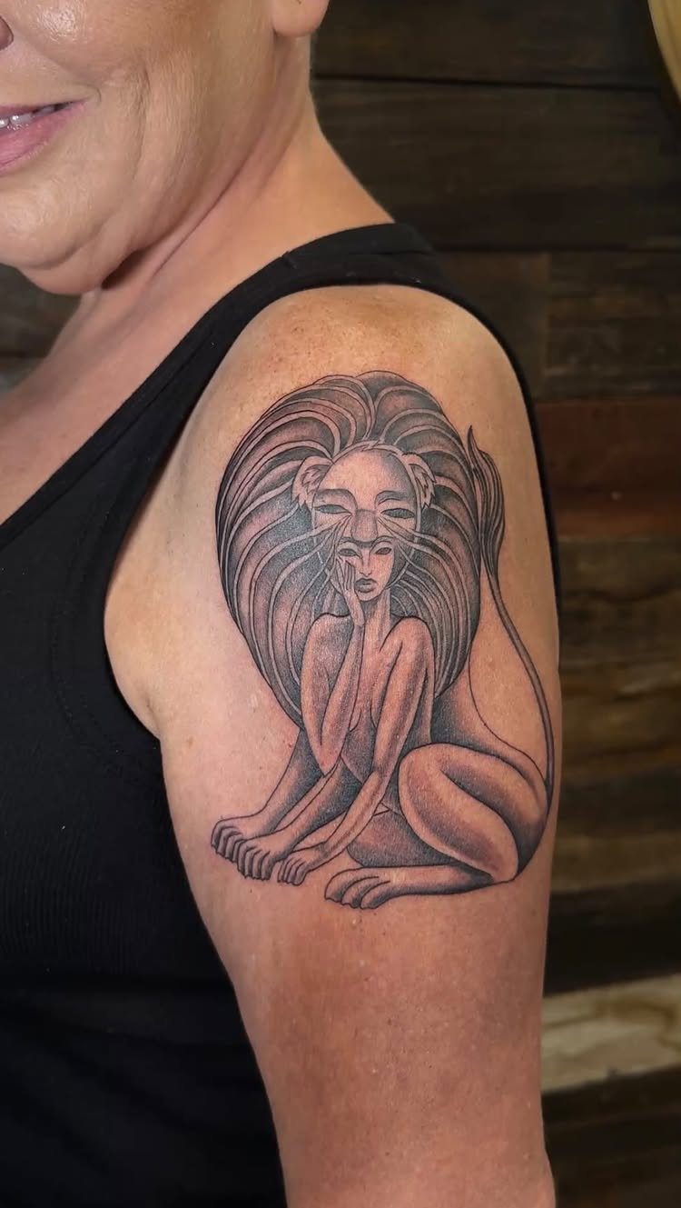 Black ink tattoo of a woman merged with a lion on an arm