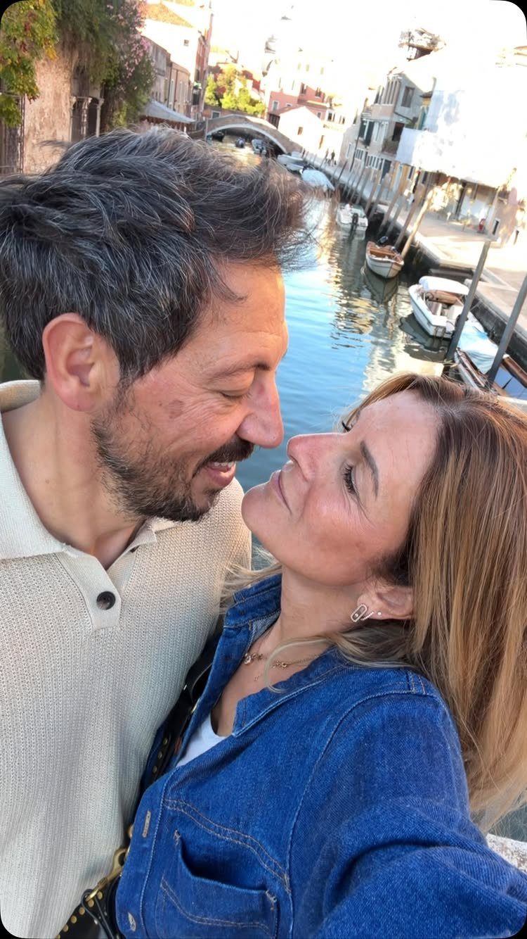 Middle-aged couple smiling together with a Venetian canal and buildings in the background
