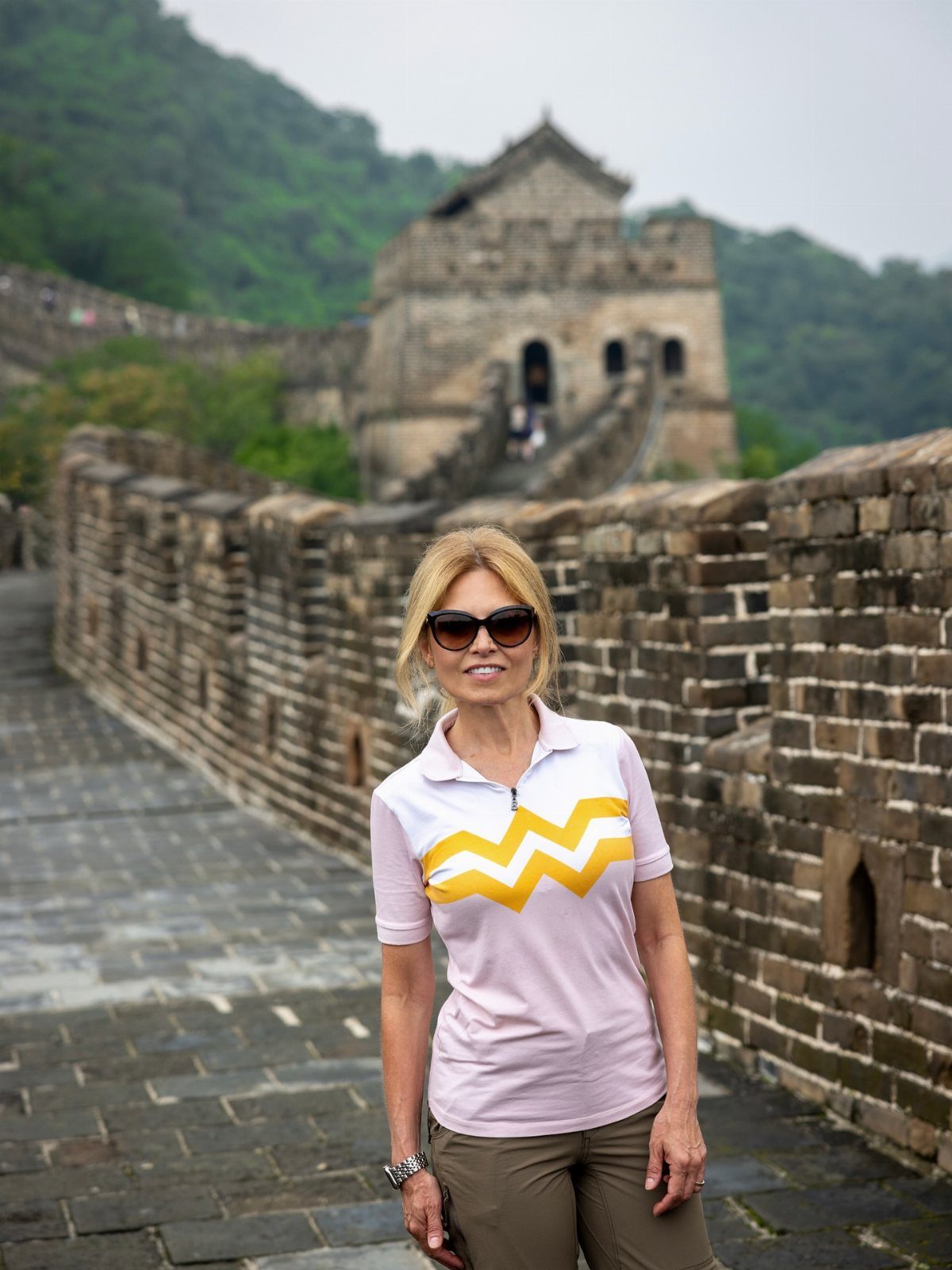 Woman in sunglasses standing on the Great Wall of China during a vacation.